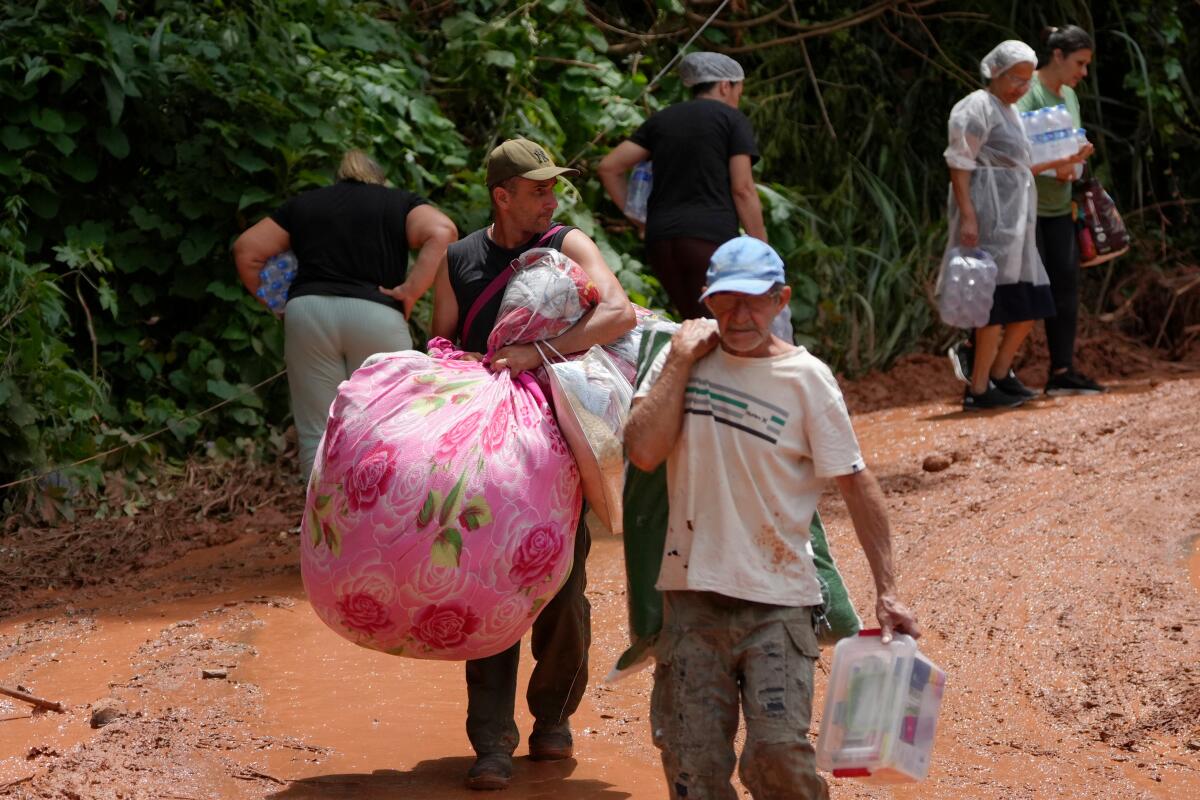 Famílias carregando pertences após enchente